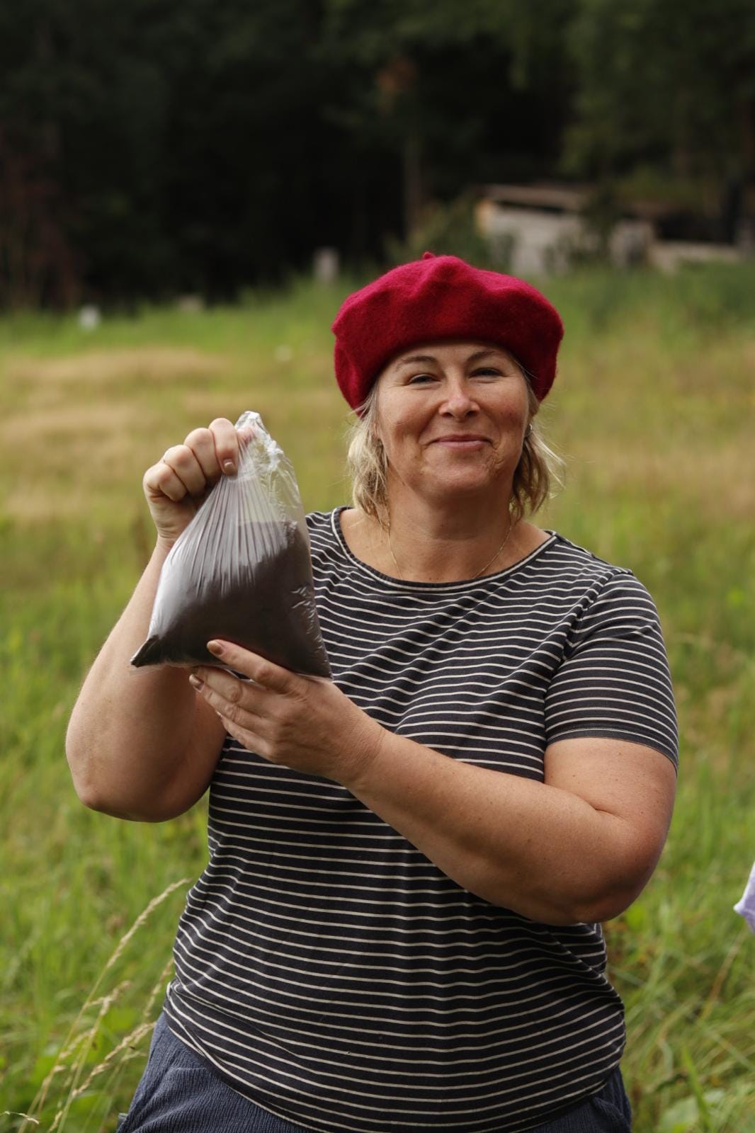 Ida met rode baret houdt een zak grond van de Zuurberg omhoog